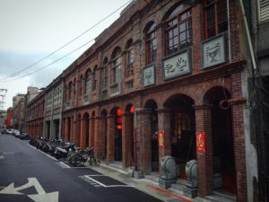 從台北橋方向拍攝十連棟。照片中的如記與陳義興非十連棟之一，因此整棟建築到三進都保留著，其深度可作為十連棟部分街屋參考。（圖片八）