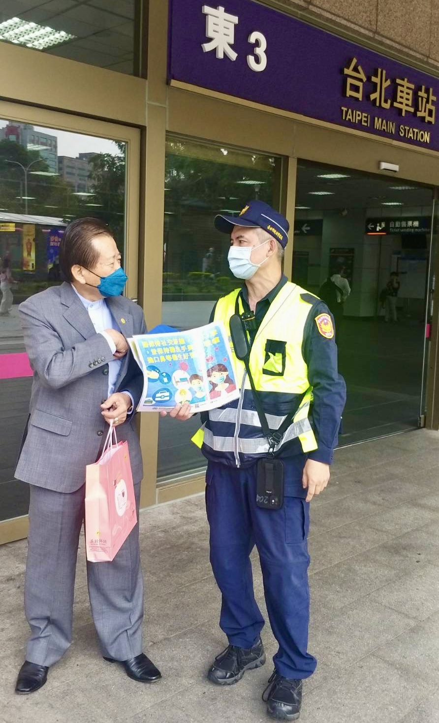 圖  臺北市保安警察大隊手持防疫宣導海報，在臺北車站各出入口處徒步巡邏，執行防疫宣導活動。