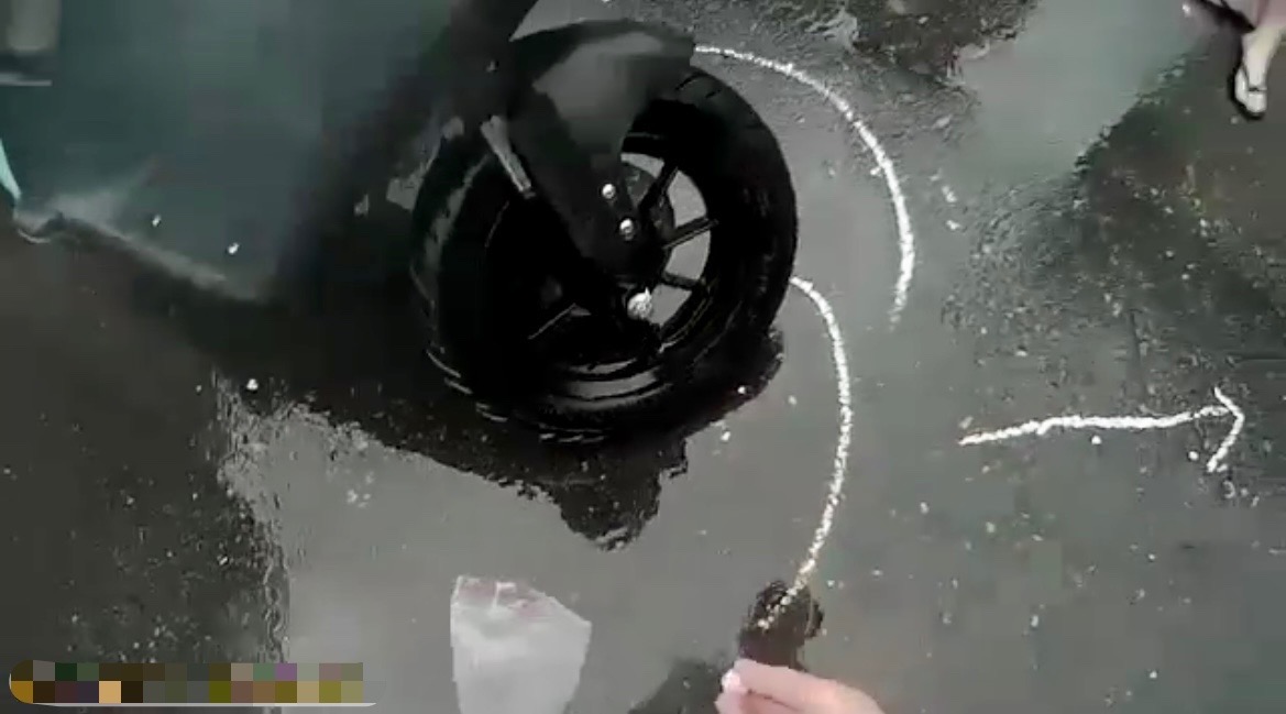 圖 因大雨狂下且車流湧現,保大員警見狀立刻在車禍現場路面,用白色粉筆劃註車輛交通事故記號及拍攝現場照片。