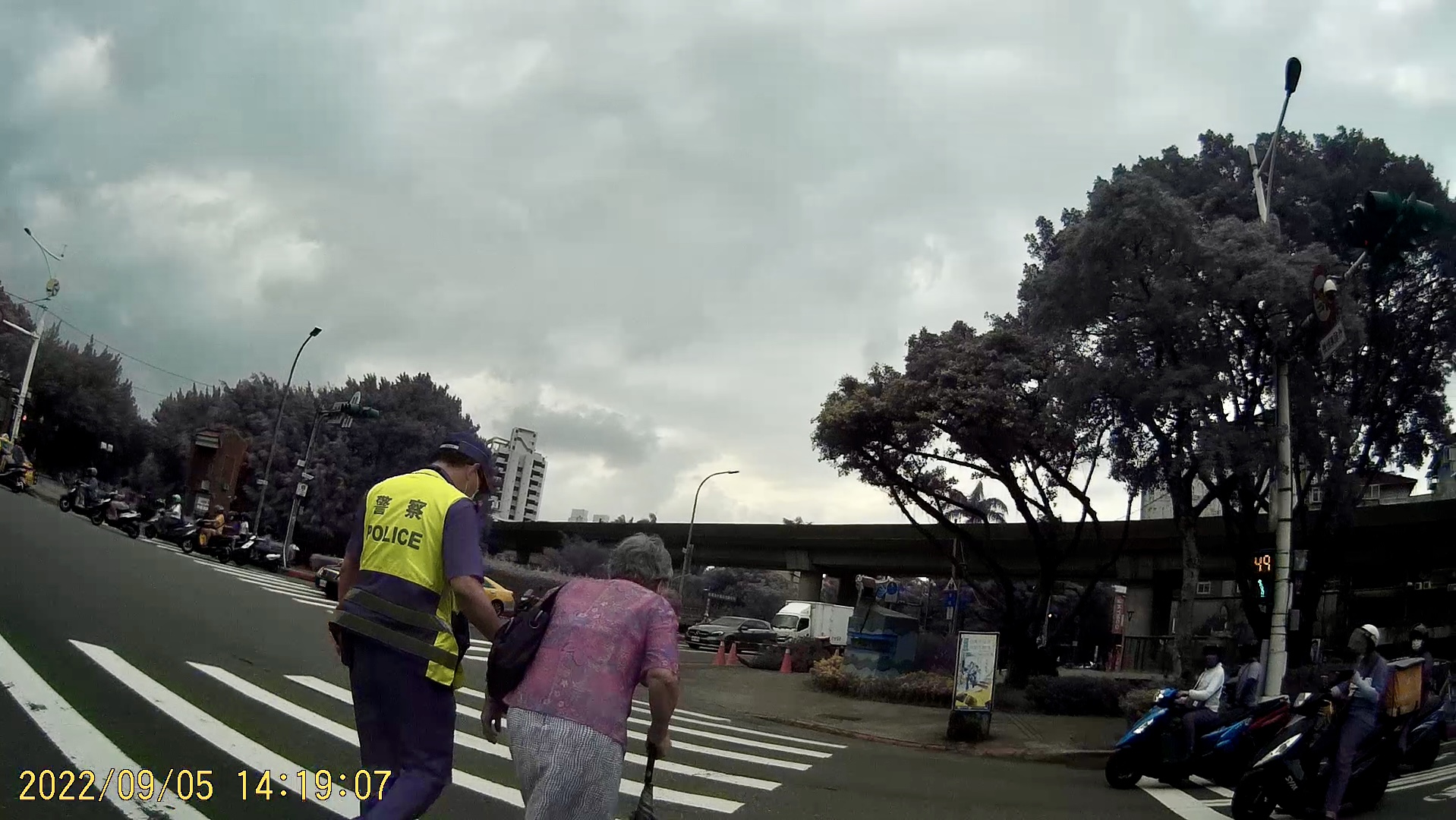 照片3-臺北市保安警察大隊吳中隊長迅速下車攙扶老婦人，等行人號誌綠燈後陪同過馬路至安全處。