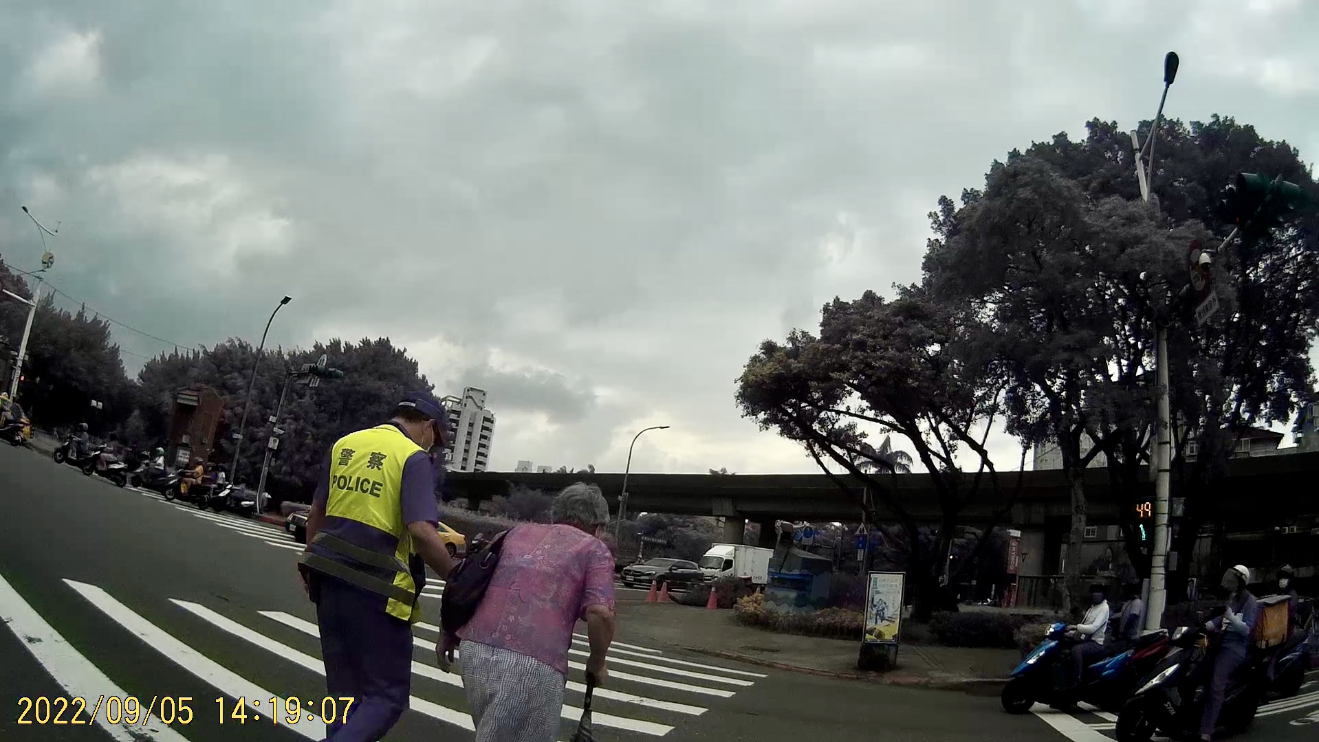 照片3-臺北市保安警察大隊吳中隊長迅速下車攙扶老婦人,等行人號誌綠燈後陪同過馬路至安全處。